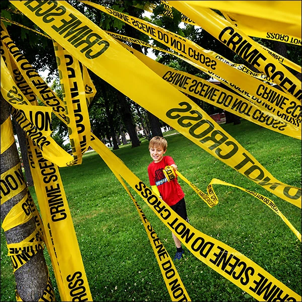 Ben Koshko adds crime scene tape Friday to a tree at City Park in Streator as part of a civic art project…, 2019.